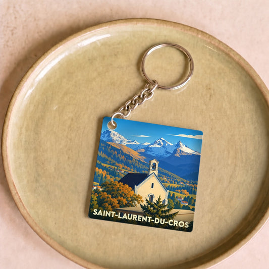 Porte-clés souvenir de la ville de Saint-Laurent-du-Cros avec une illustration stylisée de son église et des montagnes.