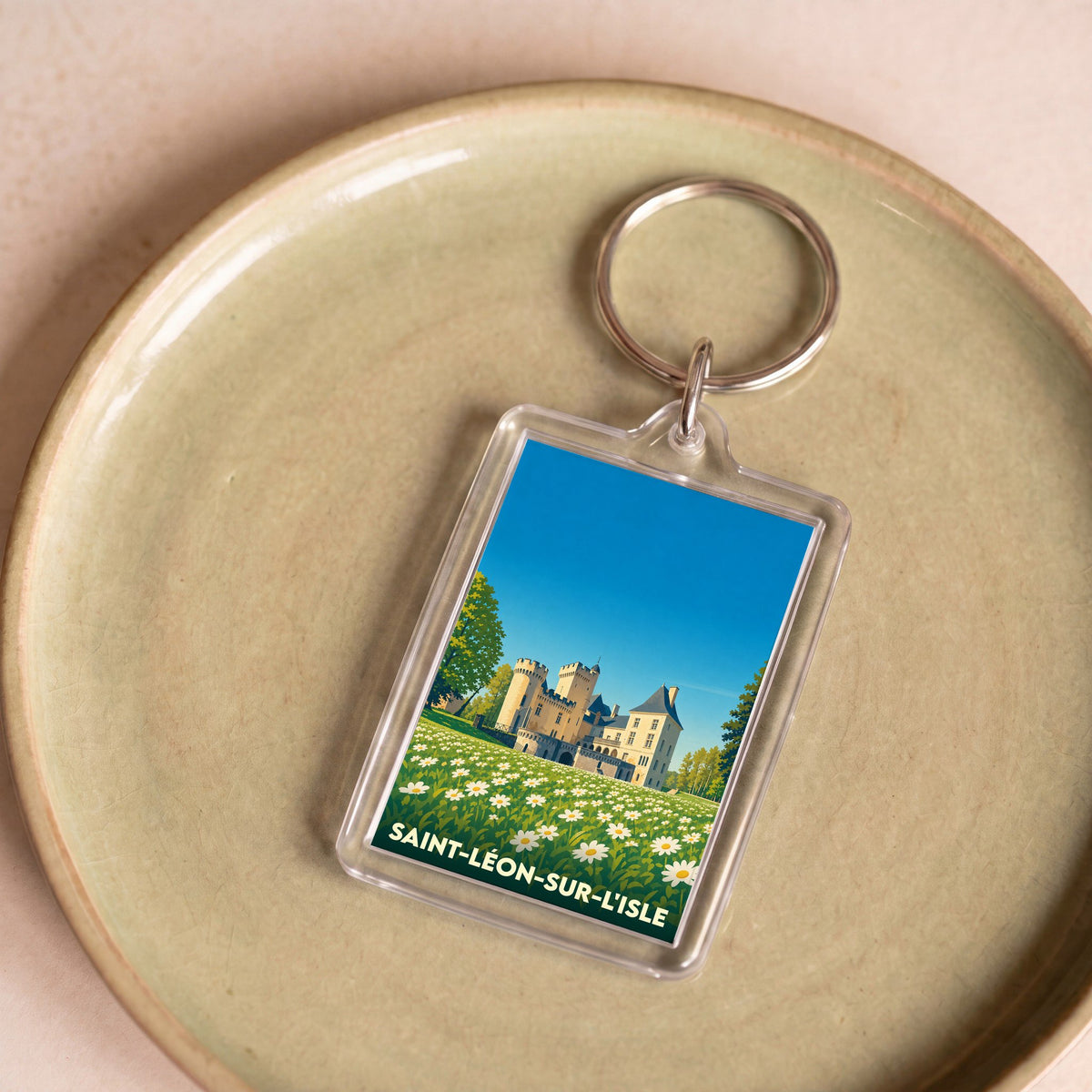 Porte-clés souvenir de la ville de Saint-Léon-sur-l'Isle avec une illustration stylisée de son château et d'un champ de fleurs.