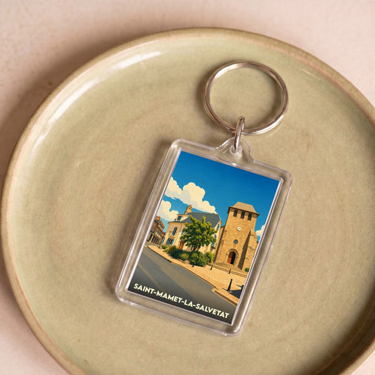 Porte-clés souvenir de la ville de Saint-Mamet-la-Salvetat avec une illustration stylisée de son église.