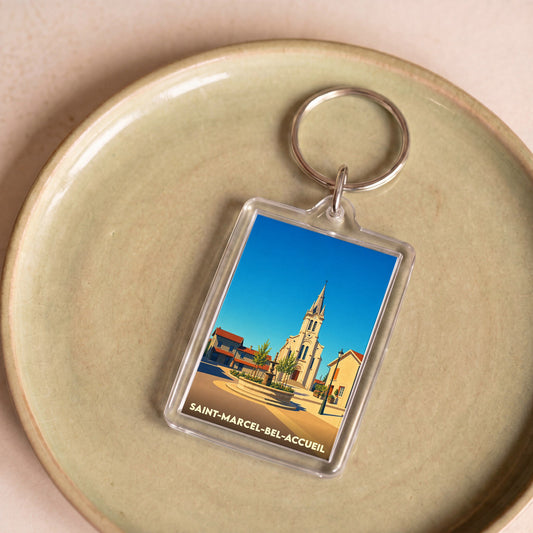 Porte-clés souvenir de la ville de Saint-Marcel-Bel-Accueil avec une illustration stylisée.