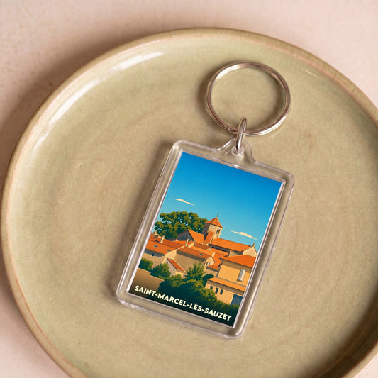 Porte-clés souvenir de Saint-Marcel-lès-Sauzet avec une illustration stylisée du village sous un ciel bleu.