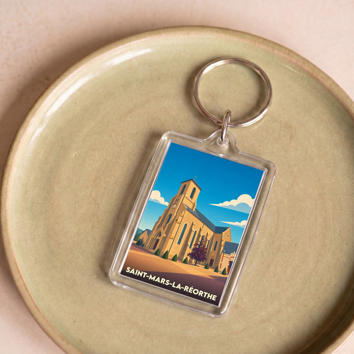 Porte-clés souvenir de la ville de Saint-Mars-la-Réorthe avec une illustration stylisée de son église.