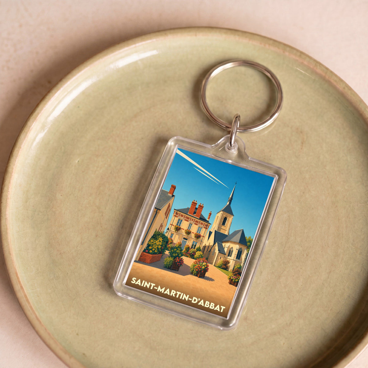 Porte-clés souvenir de la ville de Saint-Martin-d'Abbat avec une illustration stylisée d'un village fleuri.