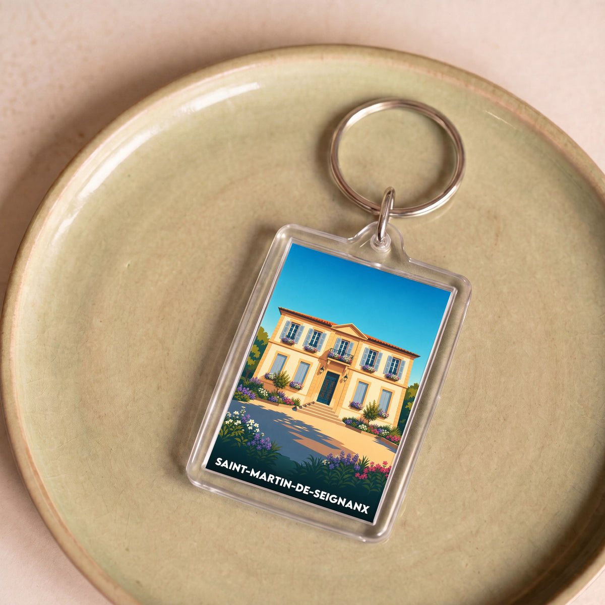 Porte-clés souvenir de la ville de Saint-Martin-de-Seignanx avec une illustration stylisée d'une maison landaise.