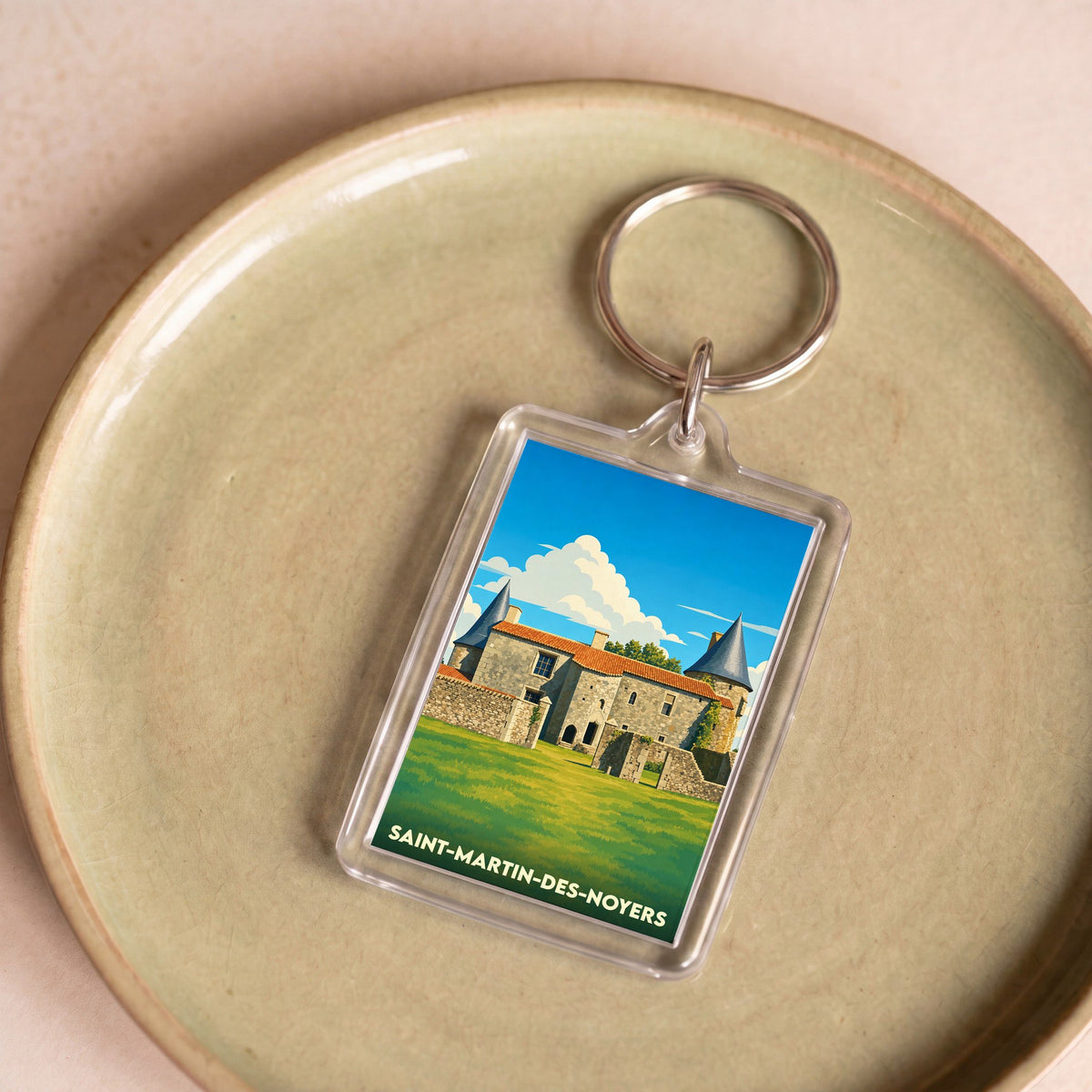 Porte-clés souvenir de la ville de Saint-Martin-des-Noyers avec une illustration stylisée de son château.