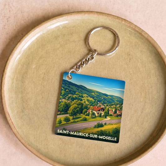 Porte-clés souvenir de la ville de Saint-Maurice-sur-Moselle avec une illustration paysagère stylisée.