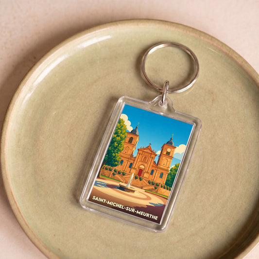 Porte-clés souvenir de la ville de Saint-Michel-sur-Meurthe avec une illustration stylisée de son église et d'une fontaine.