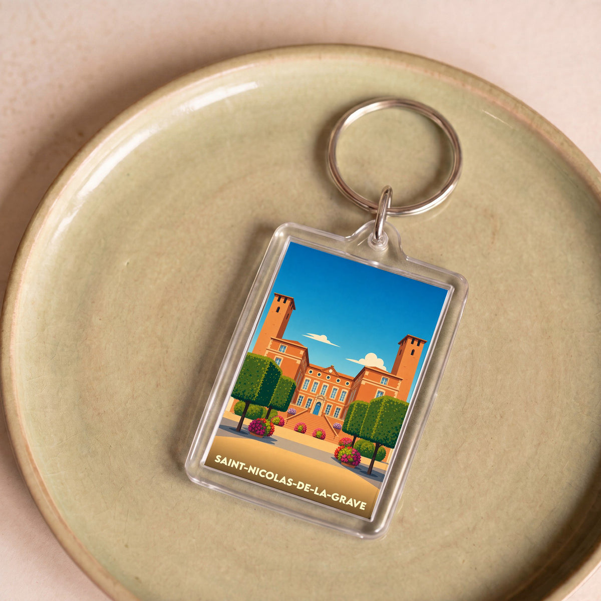 Porte-clés souvenir de la ville de Saint-Nicolas-de-la-Grave avec une illustration stylisée de son château.