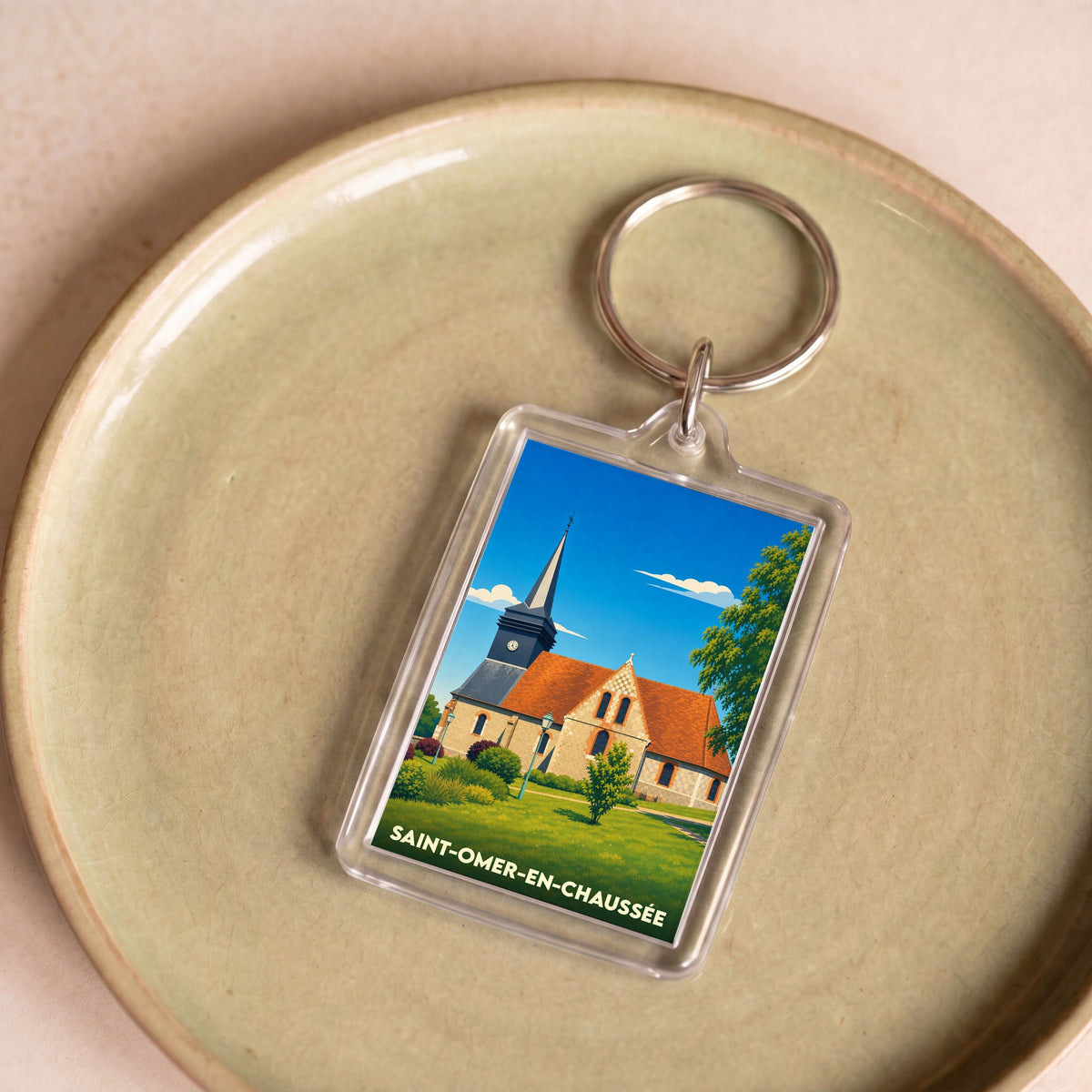Porte-clés souvenir de la ville de Saint-Omer-en-Chaussée avec une illustration stylisée de son église.