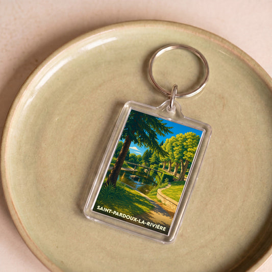Porte-clés souvenir de la ville de Saint-Pardoux-la-Rivière avec une illustration stylisée de son paysage verdoyant au bord de l'eau.