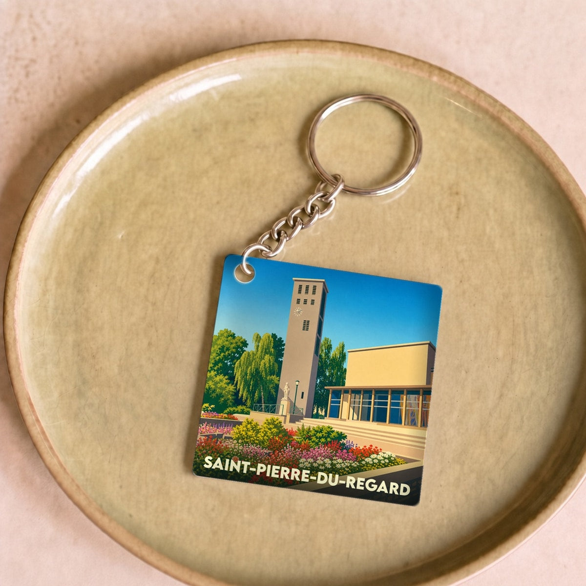 Porte-clés souvenir de la ville de Saint-Pierre-du-Regard avec une illustration stylisée.