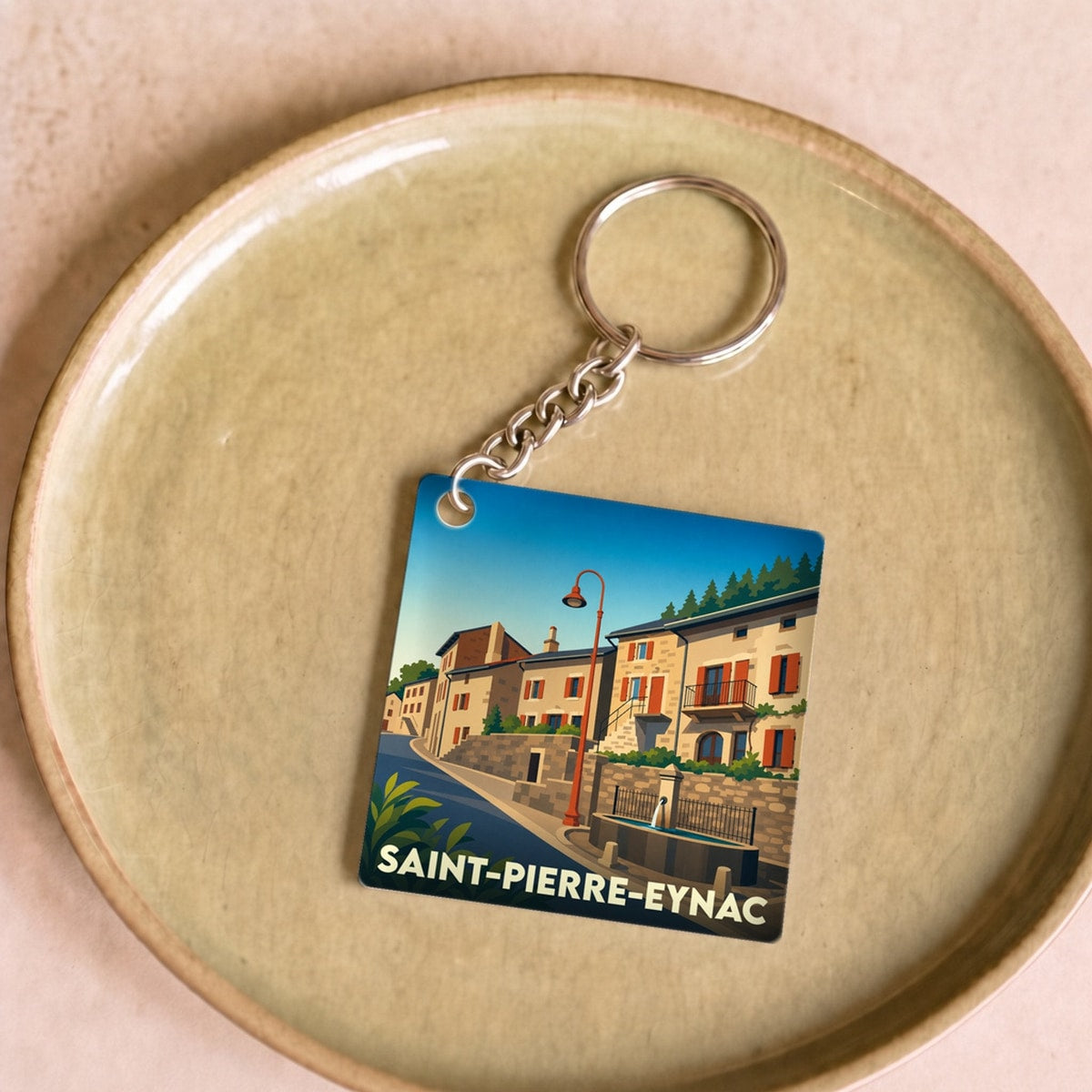 Porte-clés souvenir de la ville de Saint-Pierre-Eynac avec une illustration stylisée.