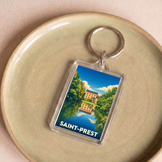 Porte-clés souvenir de la ville de Saint-Prest avec une illustration stylisée d'un manoir se reflétant dans l'eau.