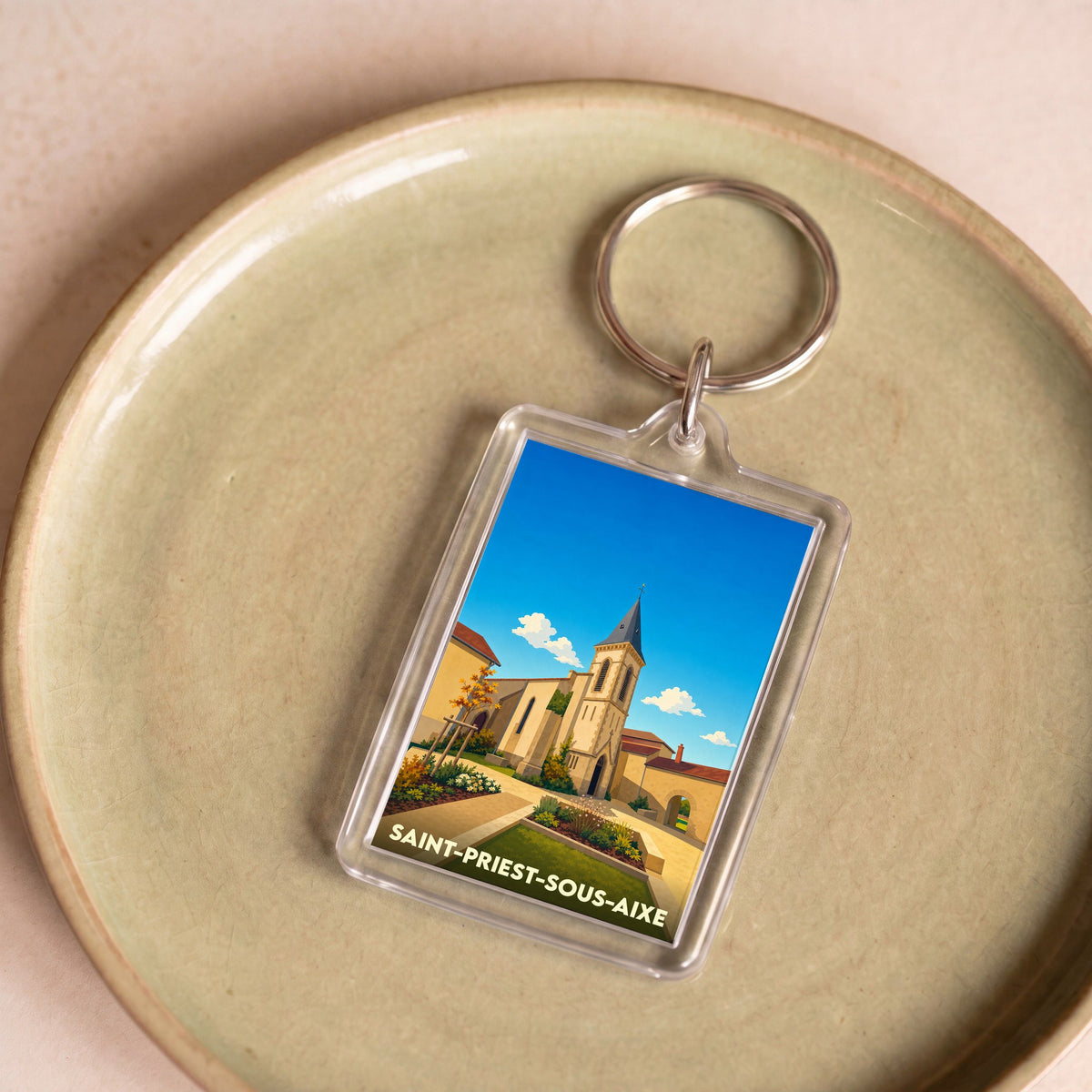 Porte-clés souvenir de la ville de Saint-Priest-sous-Aixe avec une illustration stylisée.
