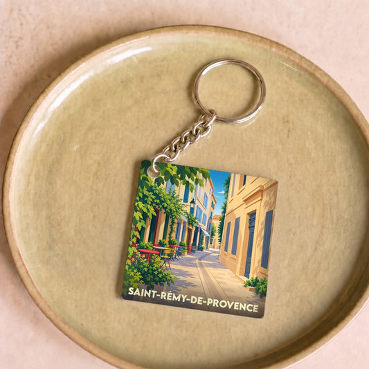 Porte-clés souvenir de la ville de Saint-Rémy-de-Provence avec une illustration stylisée d'une ruelle provençale.