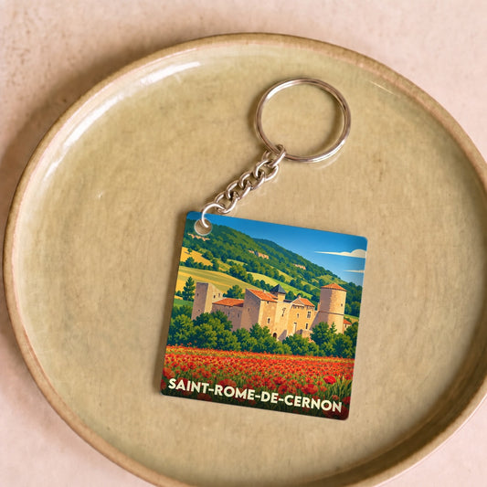 Porte-clés souvenir de la ville de Saint-Rome-de-Cernon avec une illustration stylisée d'un château au-dessus d'un champ de coquelicots.