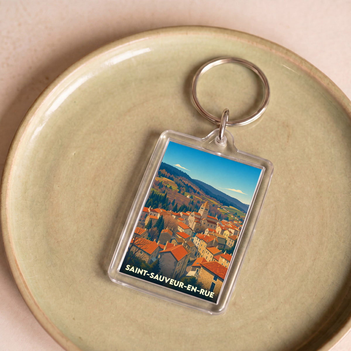 Porte-clés souvenir de la ville de Saint-Sauveur-en-Rue avec une illustration stylisée.