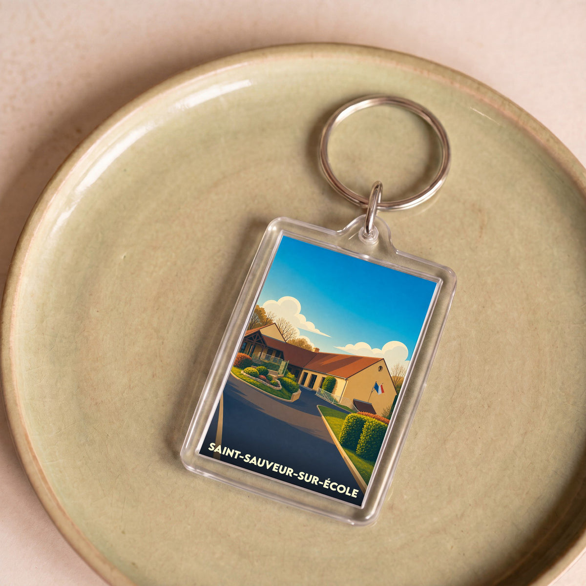 Porte-clés souvenir de la ville de Saint-Sauveur-sur-École avec une illustration stylisée.