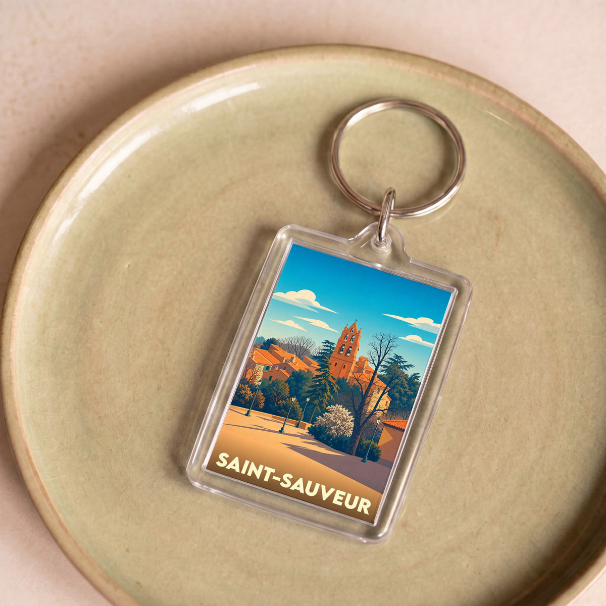 Porte-clés souvenir de la ville de Saint-Sauveur avec une illustration stylisée.