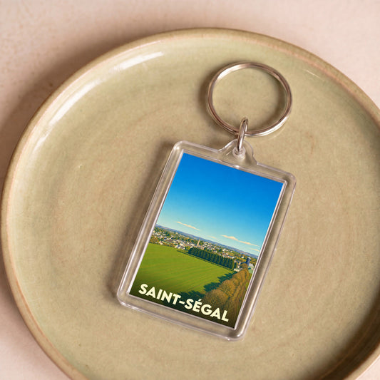 Porte-clés souvenir de la ville de Saint-Ségal avec une illustration paysagère stylisée.