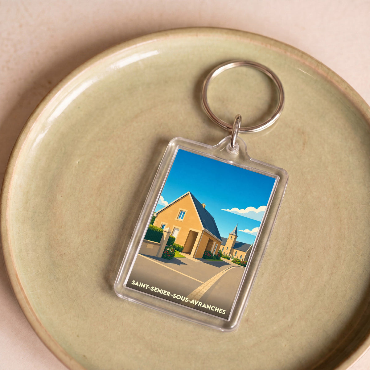 Porte-clés souvenir de la ville de Saint-Senier-sous-Avranches avec une illustration stylisée.