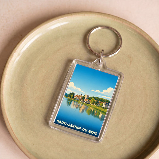 Porte-clés souvenir de la ville de Saint-Sernin-du-Bois avec une illustration stylisée d'un paysage au bord de l'eau.