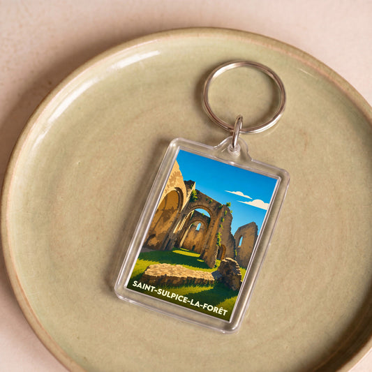 Porte-clés souvenir de la ville de Saint-Sulpice-la-Forêt avec une illustration stylisée d'une abbaye en ruines.