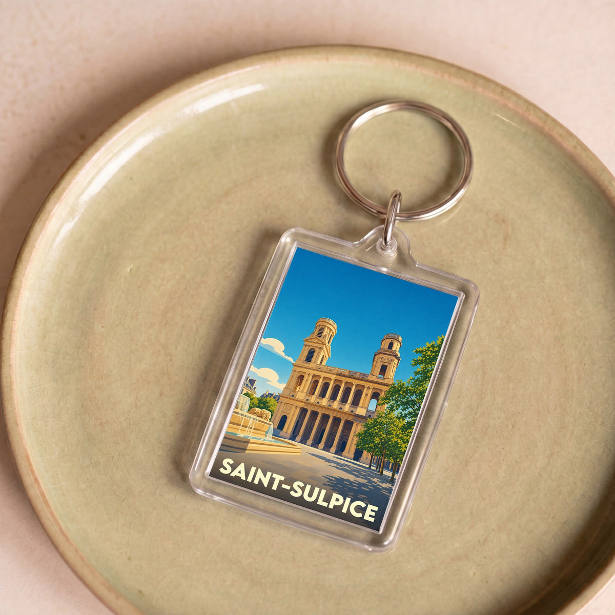 Porte-clés souvenir de Saint-Sulpice avec une illustration stylisée de son église et de sa fontaine.