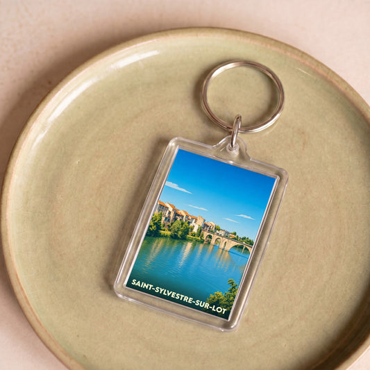 Porte-clés souvenir de la ville de Saint-Sylvestre-sur-Lot avec une illustration stylisée de son pont et de ses bords de rivière.