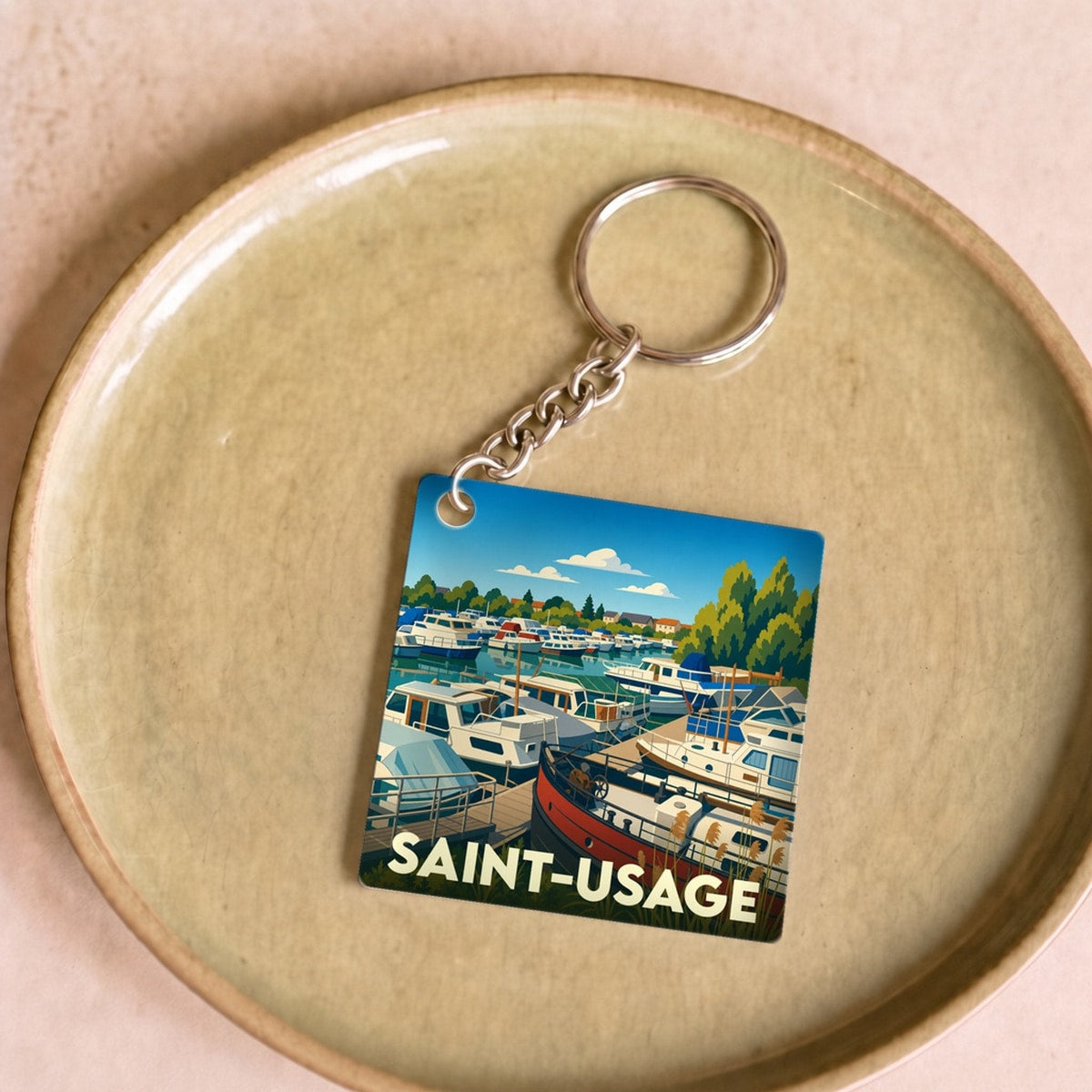 Porte-clés souvenir de la ville de Saint-Usage avec une illustration stylisée de son port de plaisance.