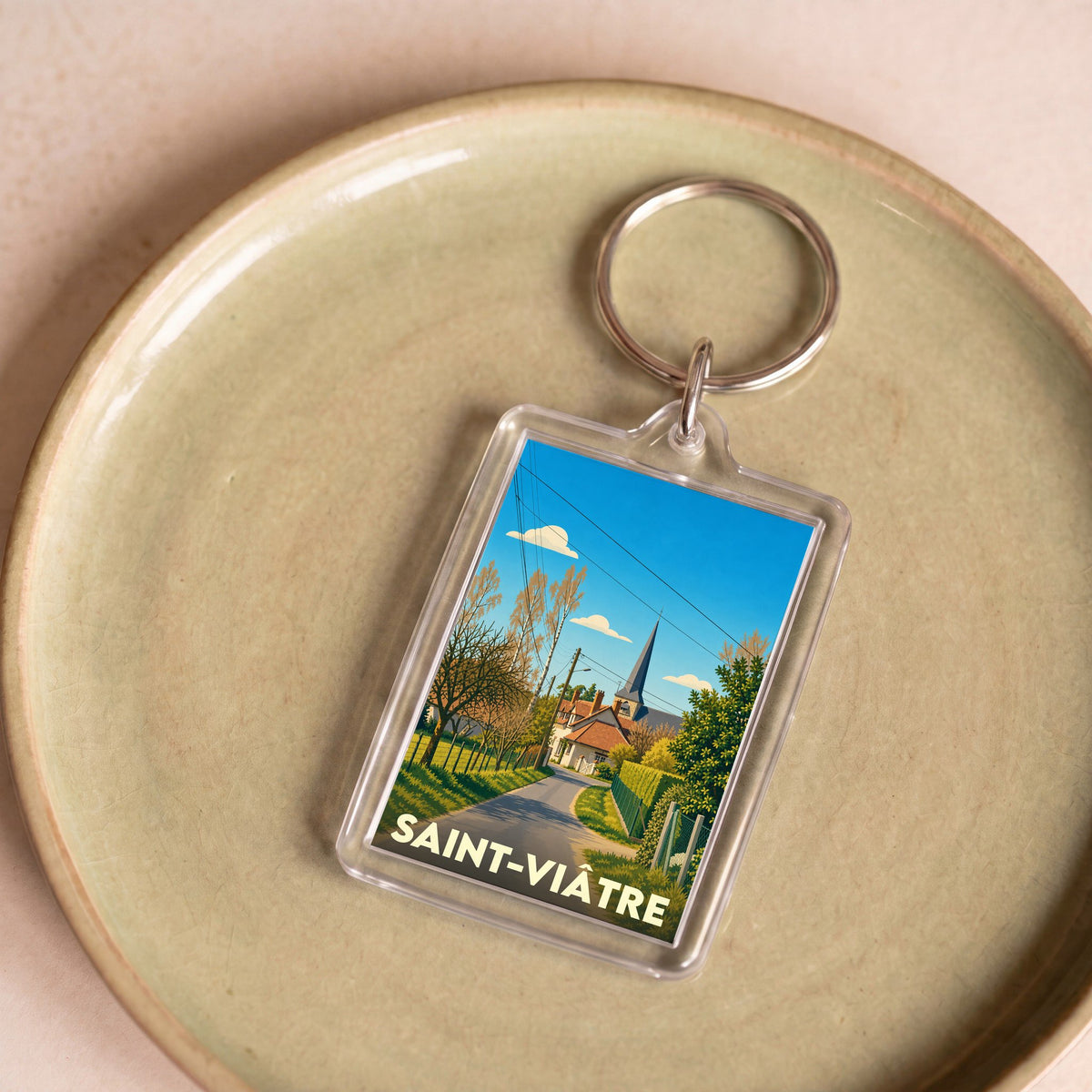 Porte-clés souvenir de la ville de Saint-Viâtre avec une illustration stylisée d'un paysage de village.