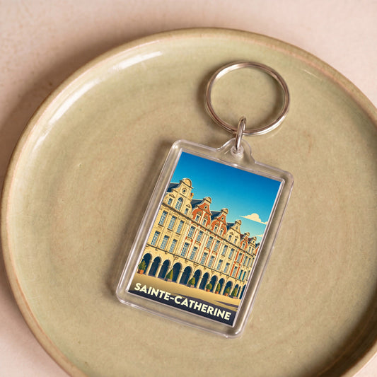 Porte-clés souvenir de la ville de Sainte-Catherine avec une illustration stylisée de bâtiments historiques.