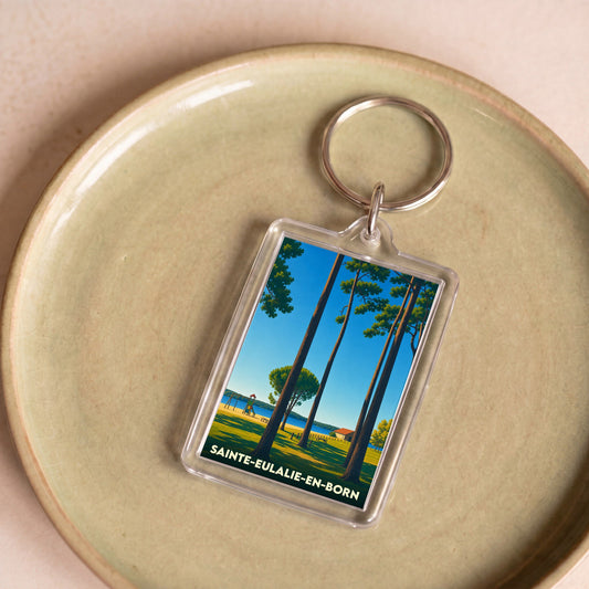 Porte-clés souvenir de la ville de Sainte-Eulalie-en-Born avec une illustration stylisée de pins au bord de l'eau.