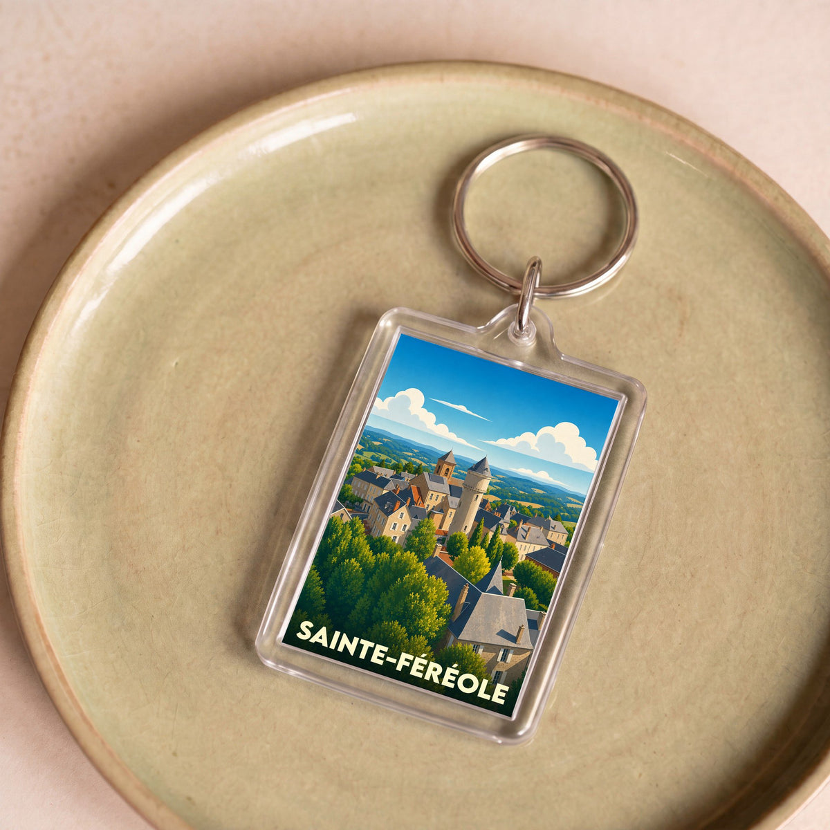 Porte-clés souvenir de la ville de Sainte-Féréole avec une illustration stylisée d'un village pittoresque.