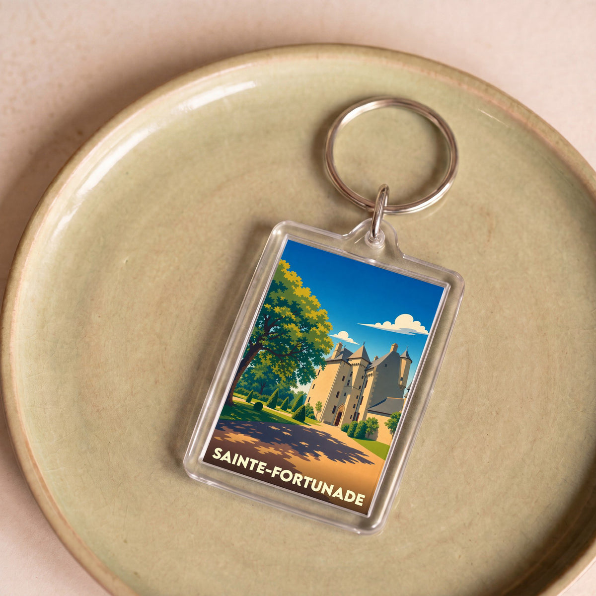 Porte-clés souvenir de la ville de Sainte-Fortunade avec une illustration stylisée de son château.