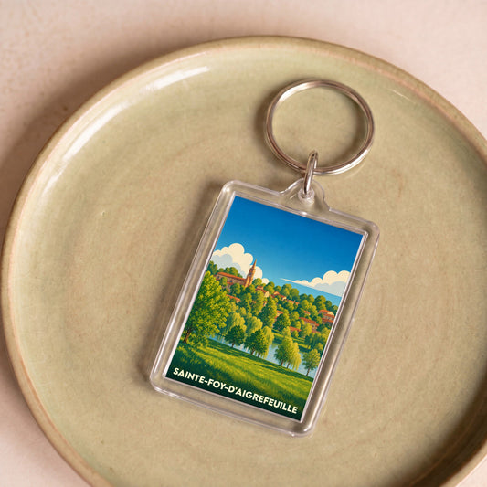Porte-clés souvenir de la ville de Sainte-Foy-d'Aigrefeuille avec une illustration paysagère colorée.