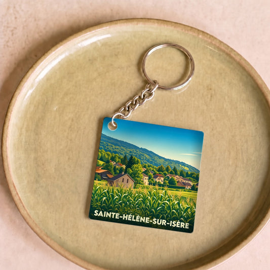 Porte-clés souvenir de Sainte-Hélène-sur-Isère avec une illustration stylisée de son paysage champêtre.