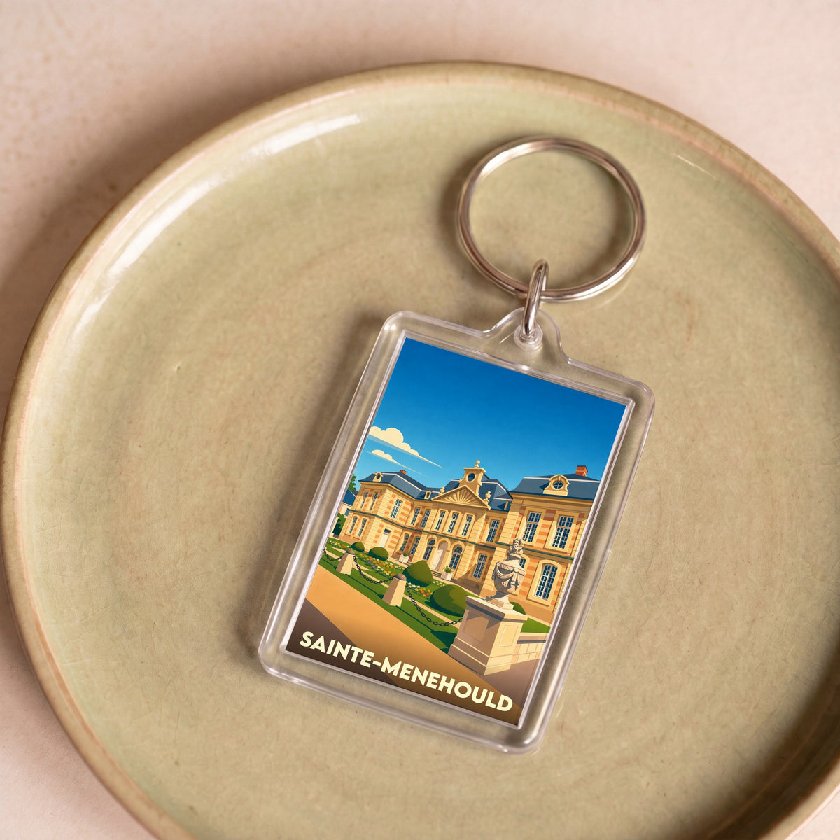 Porte-clés souvenir de la ville de Sainte-Menehould avec une illustration stylisée de son hôtel de ville.