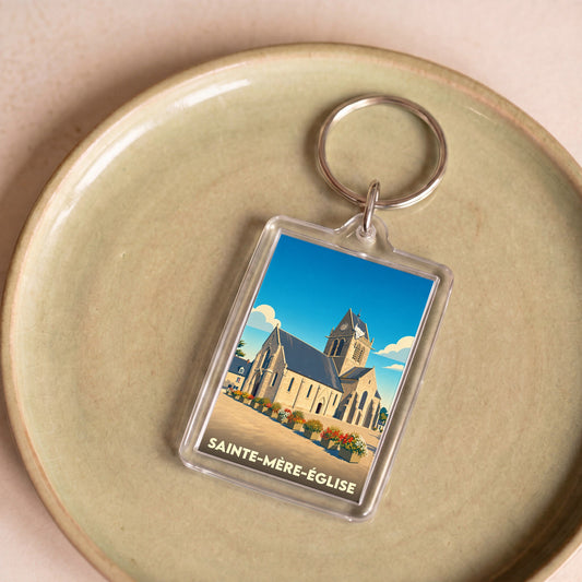 Porte-clés souvenir de la ville de Sainte-Mère-Église avec une illustration stylisée de son église.