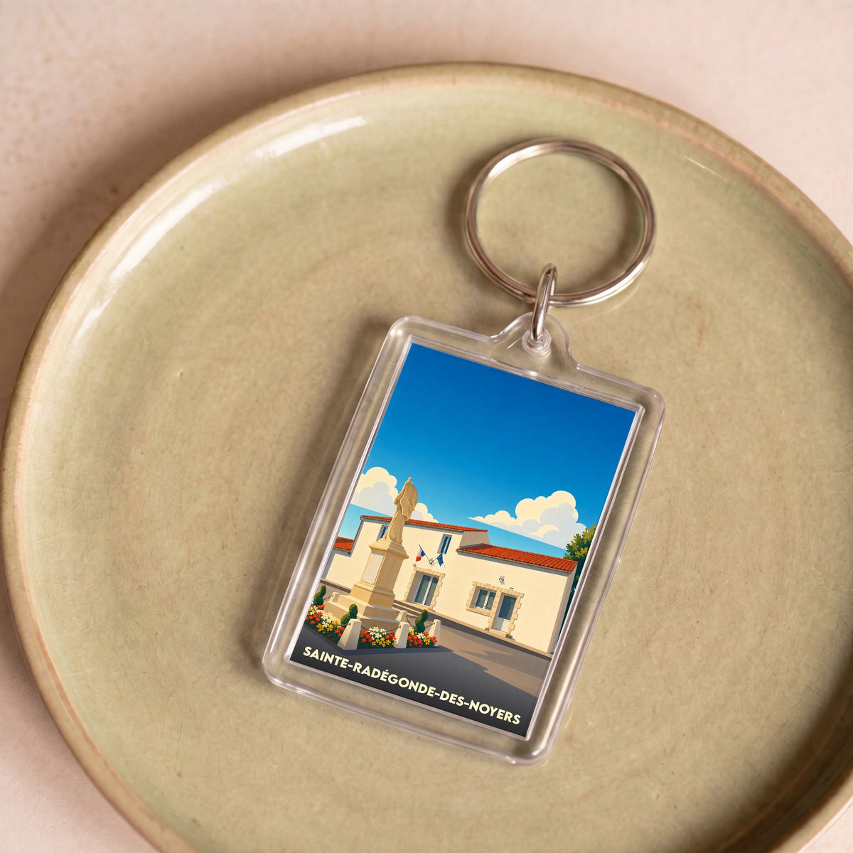 Porte-clés souvenir de la ville de Sainte-Radégonde-des-Noyers avec une illustration stylisée.
