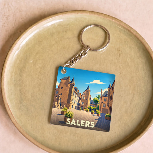 Porte-clés souvenir de la ville de Salers avec une illustration stylisée de ses bâtiments historiques.