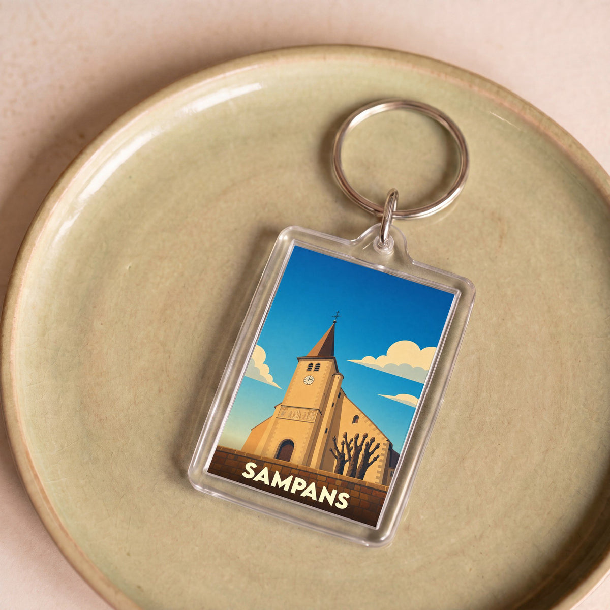 Porte-clés souvenir de la ville de Sampans avec une illustration stylisée de son église.