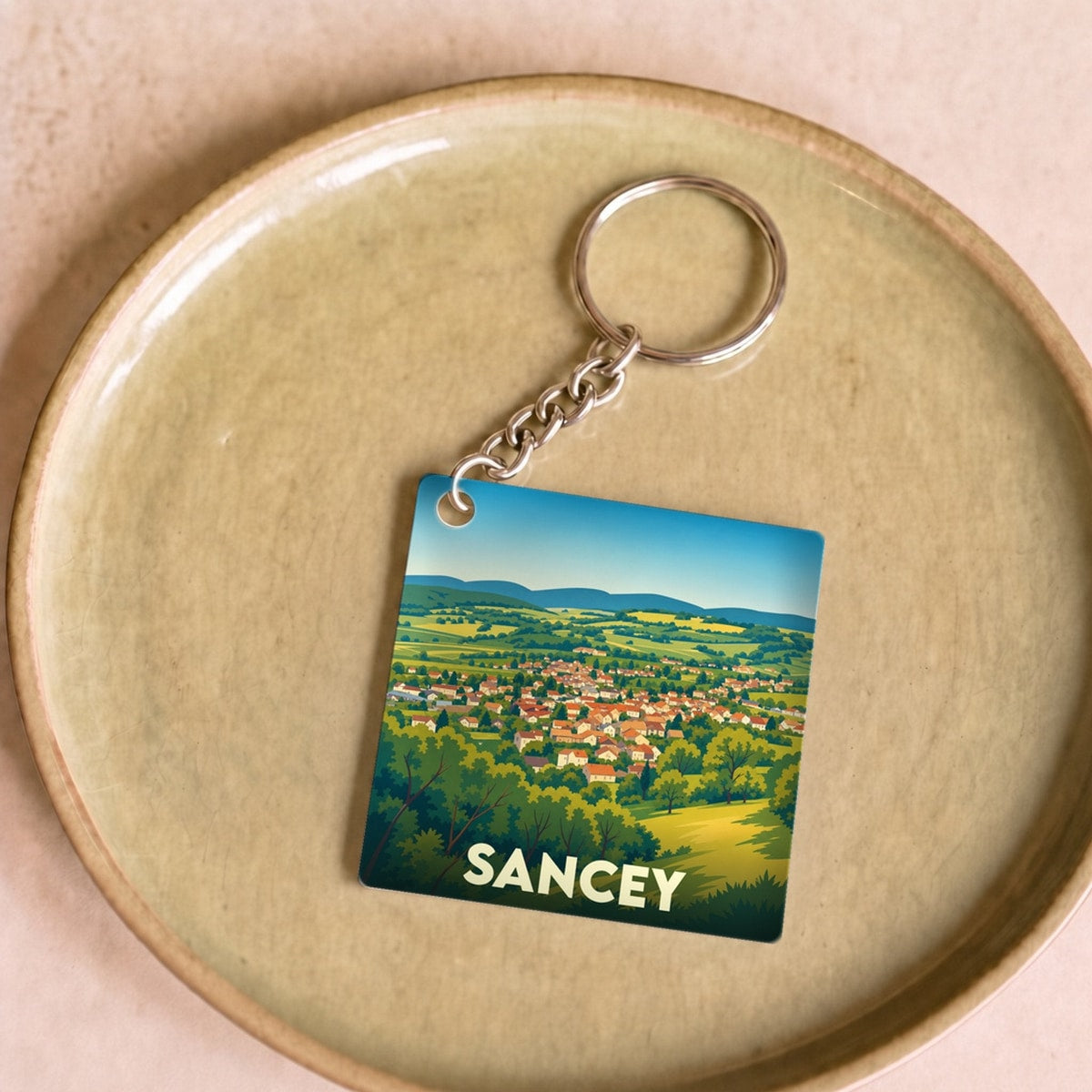 Porte-clés souvenir de la ville de Sancey avec une illustration stylisée de son paysage.