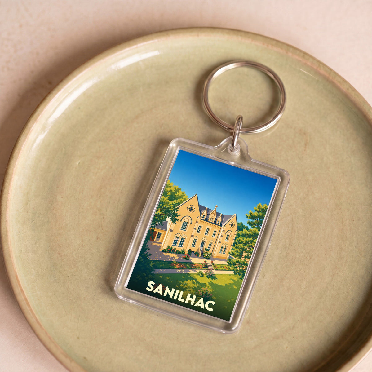Porte-clés souvenir de la ville de Sanilhac avec une illustration stylisée d'un bâtiment historique.