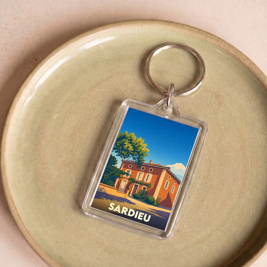 Porte-clés souvenir de la ville de Sardieu avec une illustration stylisée d'une maison traditionnelle.