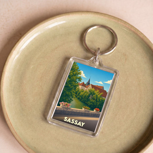 Porte-clés souvenir de la ville de Sassay avec une illustration stylisée d'un paysage urbain.