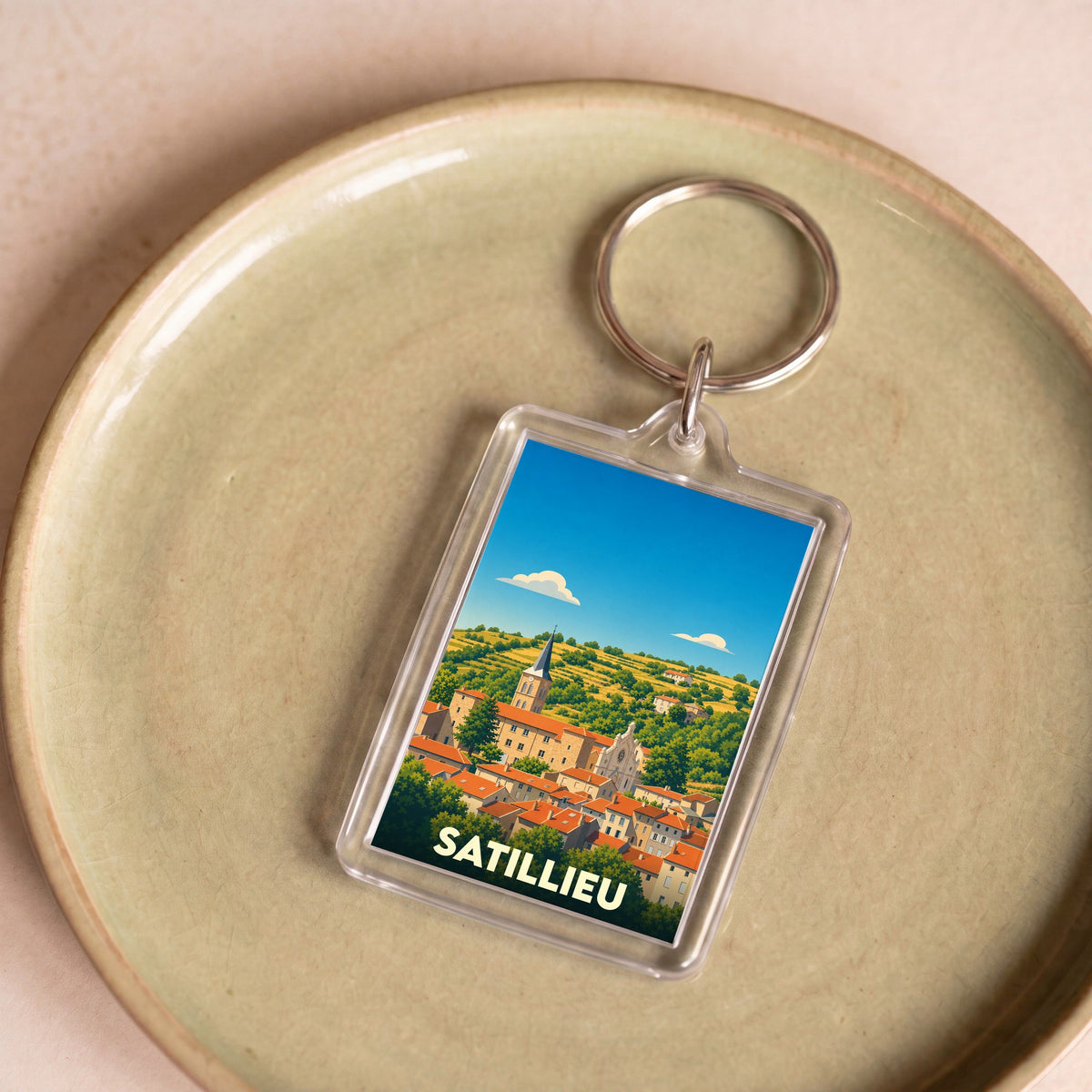 Porte-clés souvenir de la ville de Satillieu avec une illustration stylisée.