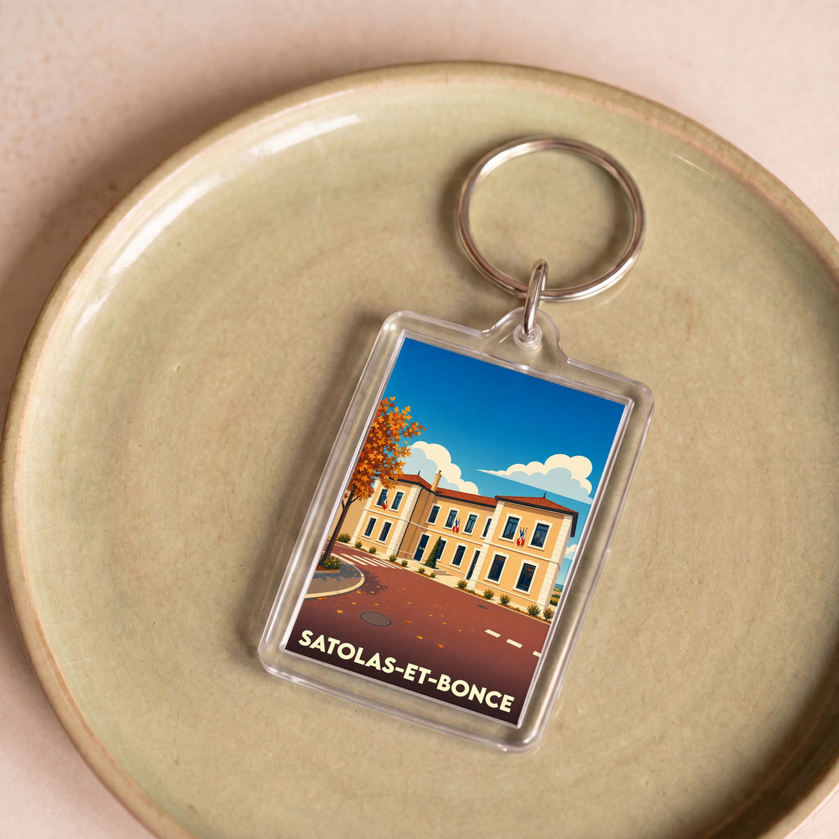Porte-clés souvenir de la ville de Satolas-et-Bonce avec une illustration stylisée de la mairie.