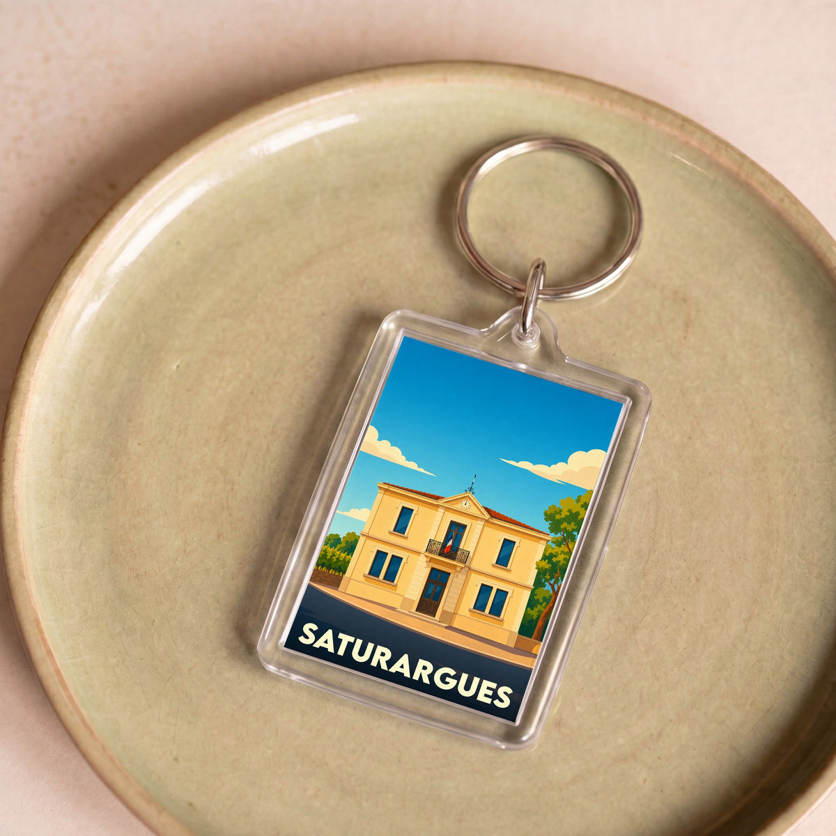 Porte-clés souvenir de la ville de Saturargues avec une illustration stylisée de sa mairie.