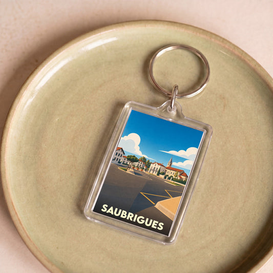 Porte-clés souvenir de la ville de Saubrigues avec une illustration stylisée.
